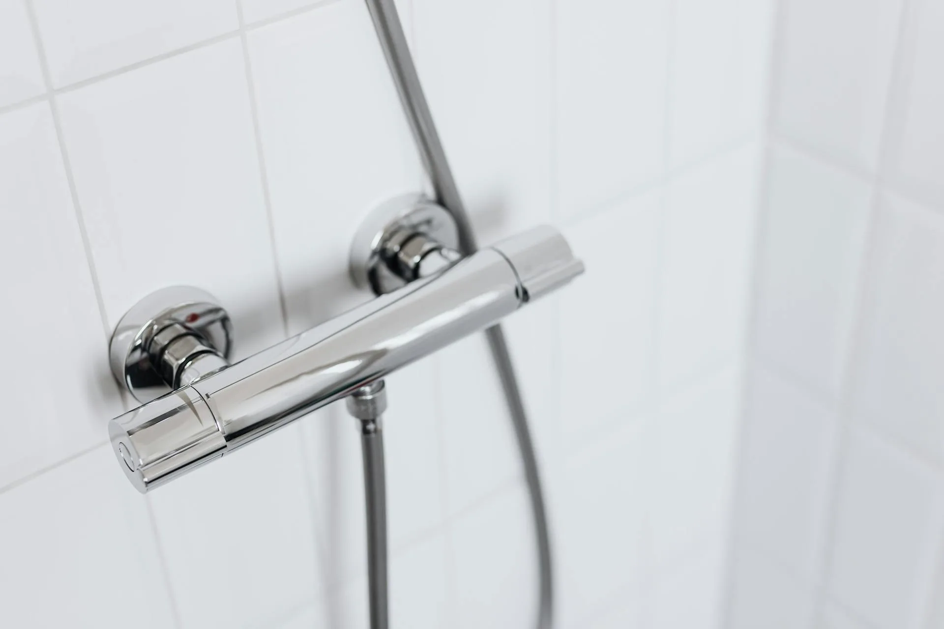Modern chrome shower fitting on white tiles
