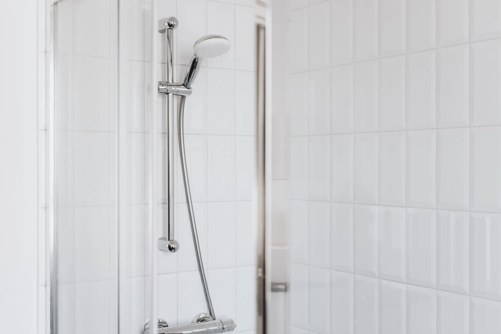 Stylish shower with chrome fixtures and clean white tiles